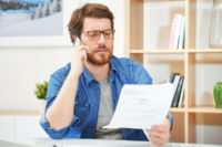 Man on the phone looking at tax paperwork
